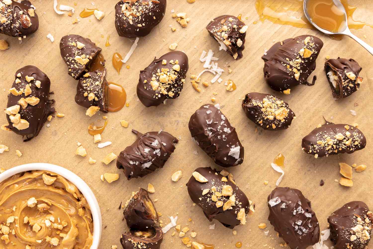 Candy Bar Dates Surrounded by Crushed Peanuts, Coconut Slivers, Caramel Sauce, and a Bowl of Peanut Butter