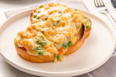 Two slices of toasted bread topped with a creamy mixture of vegetables and chicken