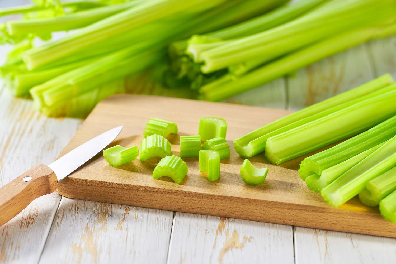 bunches of celery, a few chopped pieces on a cutting board