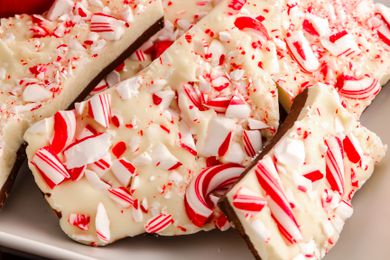 Chocolate peppermint bark candy on white plate with red snowflake mug filled with hot cocoa for Santa