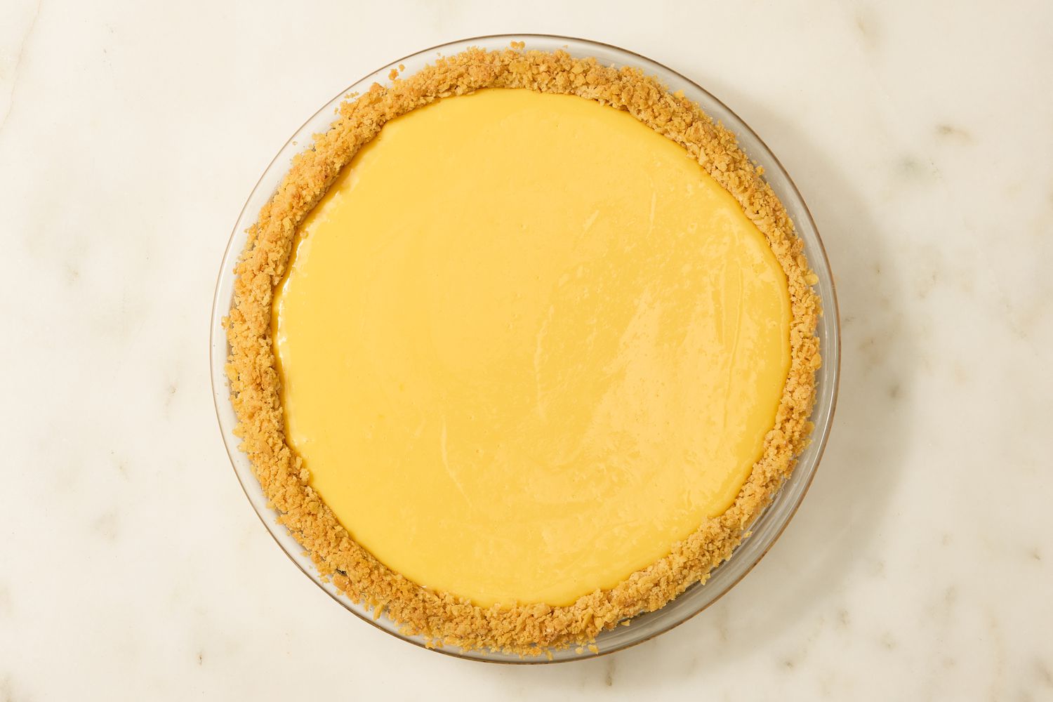 Overhead view of the crust and filling for Atlantic Beach Pie recipe in a glass pie dish on a marble countertop
