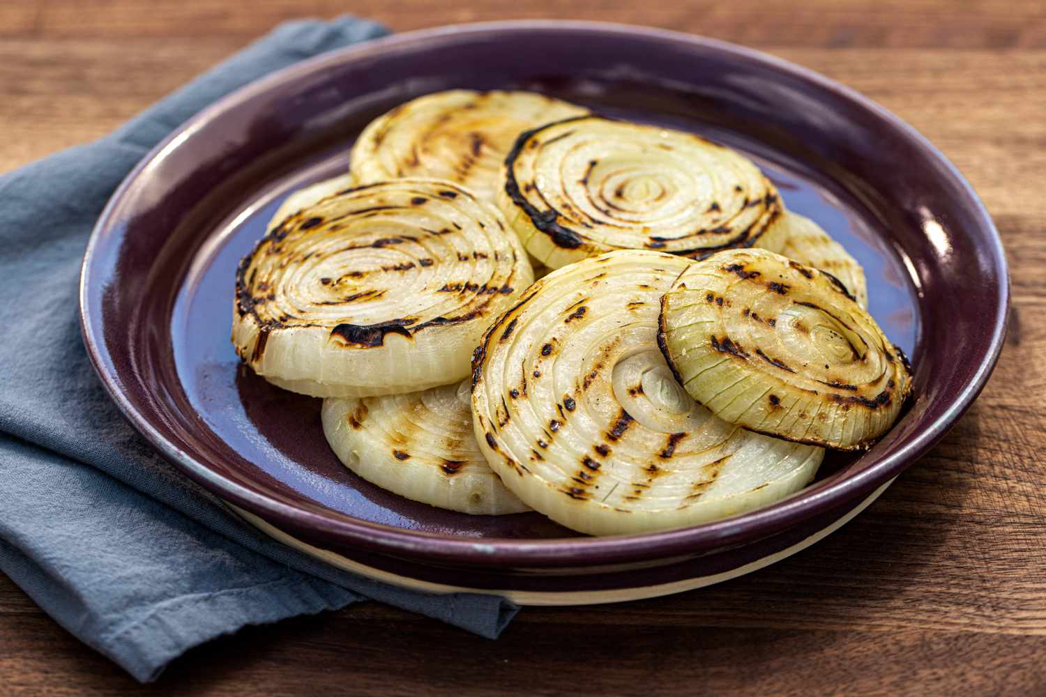 The best ever grilled onions piled on a purple rimmed platter.