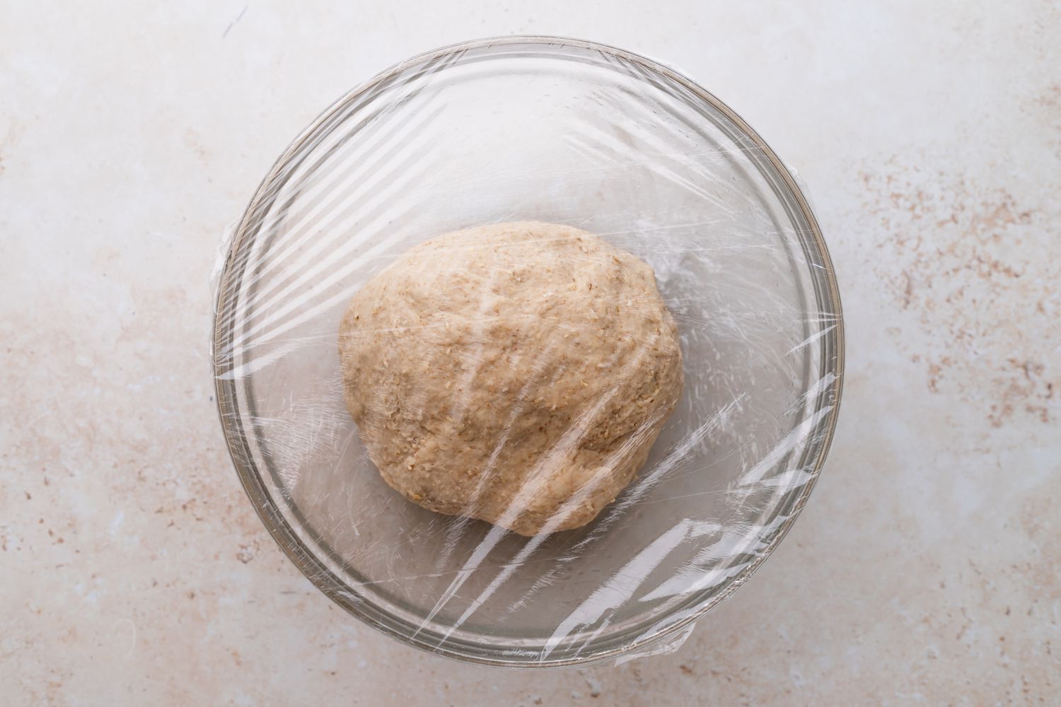 Dough for oat bread rising in a bowl to show how to make oatmeal bread.