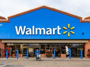Exterior of a Walmart store with a person pushing a shopping cart in front