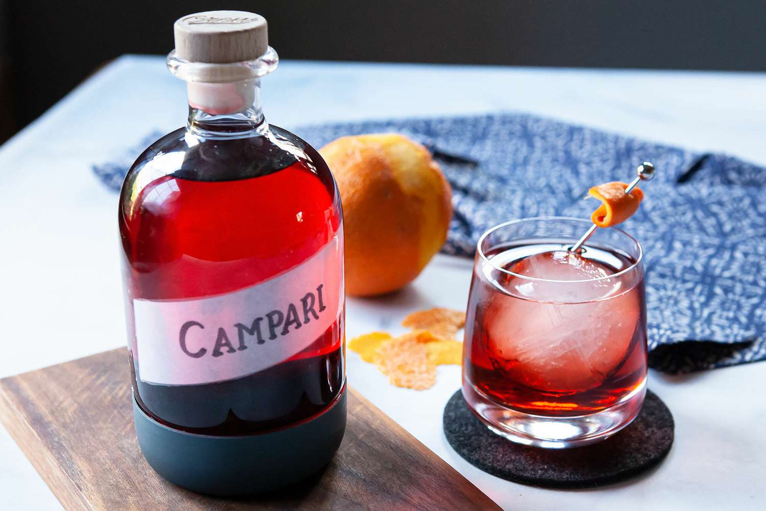 Glass jar filled with Campari substitute. A whiskey glass with a cocktail inside is to the right.