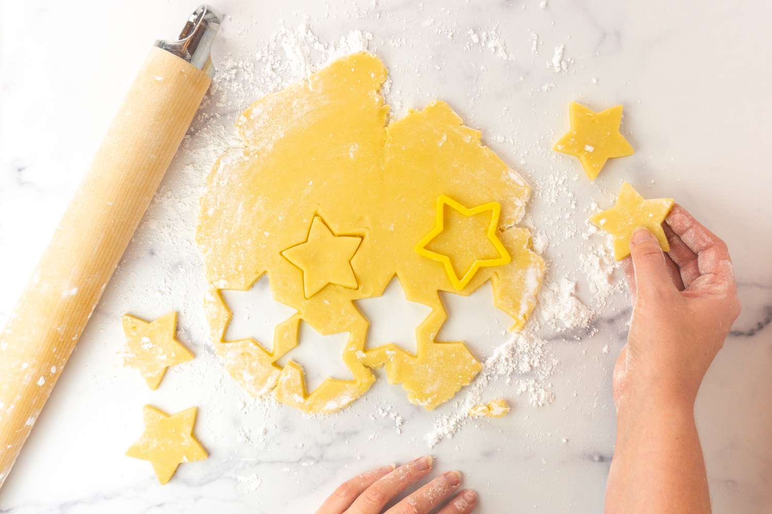 Person cutting starshaped cookies out of dough using a cookie cutter