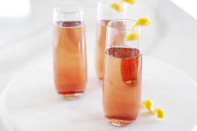 Side view of kir royale in three tall and slender glasses on a white background