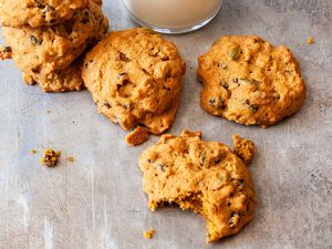 Pumpkin spice cookies stacked on a counter with a glass of milk in the background