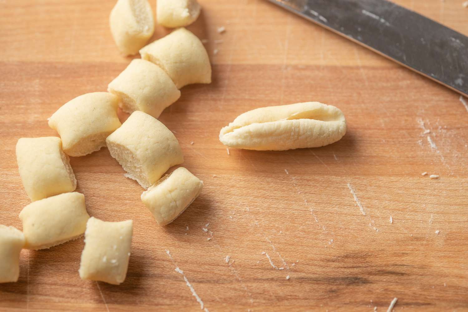 Cavatelli Formed: Serrated Knife Rolling Piece of Dough on the Counter, and on the Counter Next to Cavatelli, More Dough Pieces
