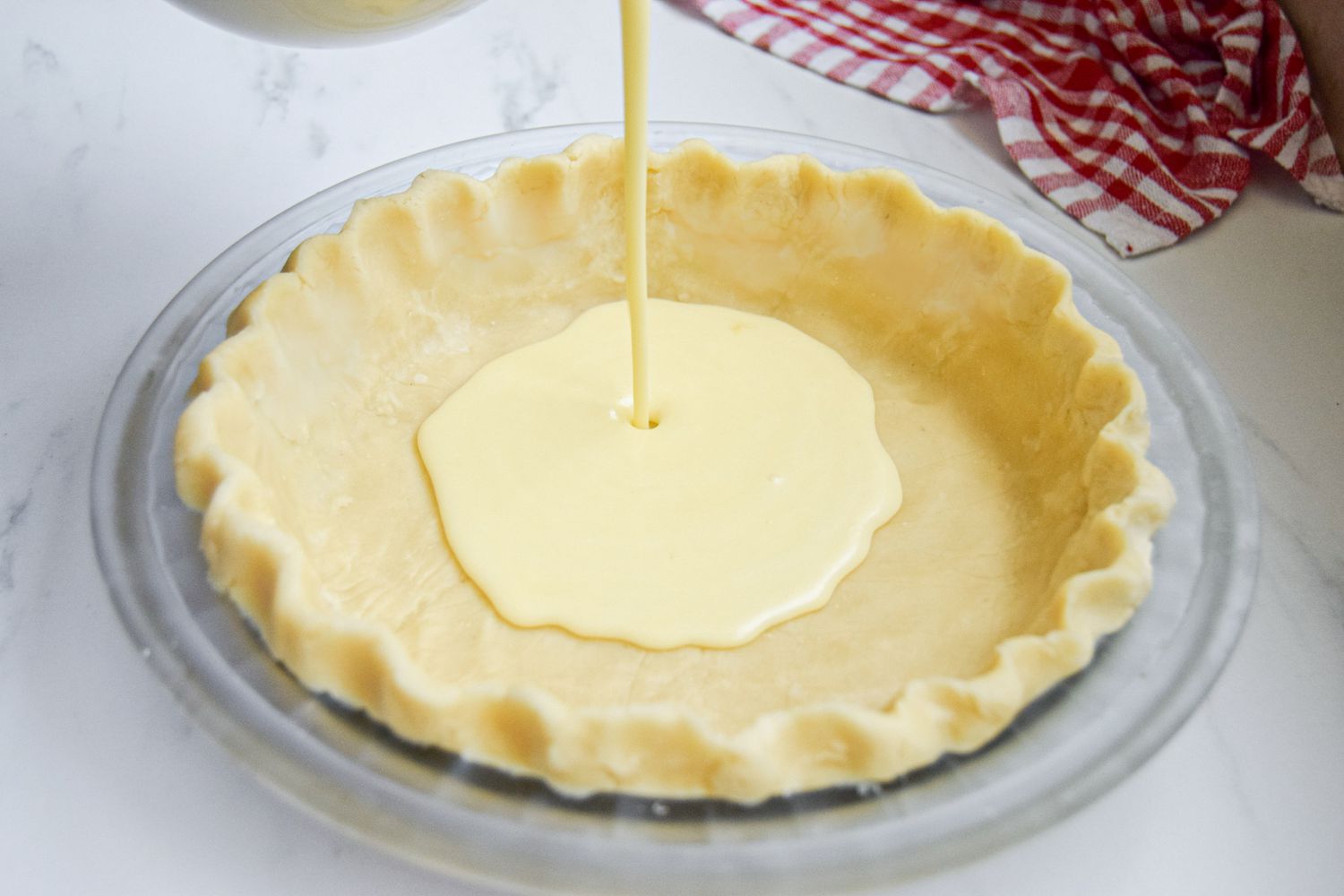 Pouring filling into a pie crust to show what is buttermilk pie.