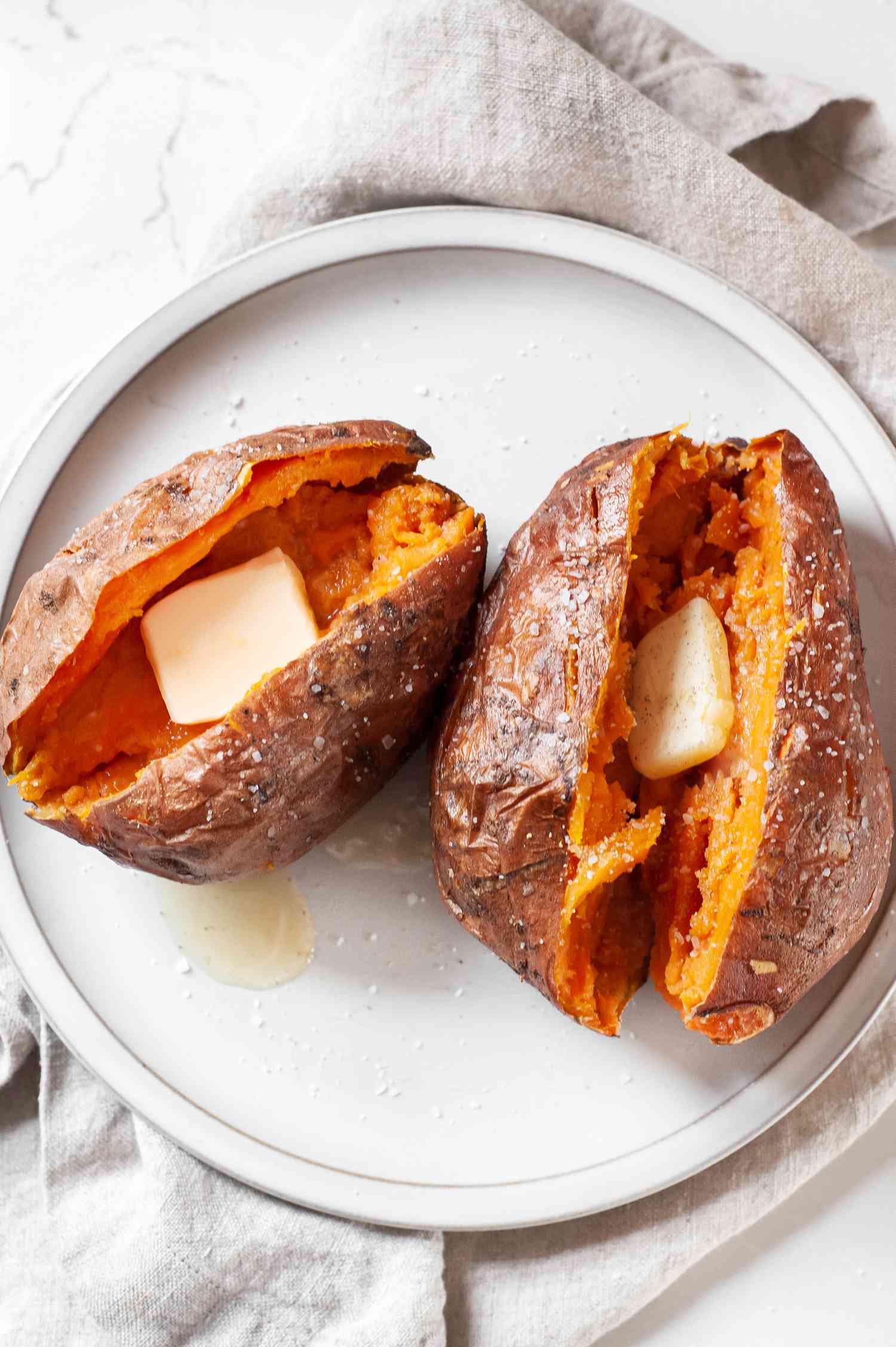 Plate with Microwave Sweet Potatoes Split in Half and Topped with a Slab of Butter and Salt 