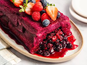 A summer pudding topped with various berries served on a platter