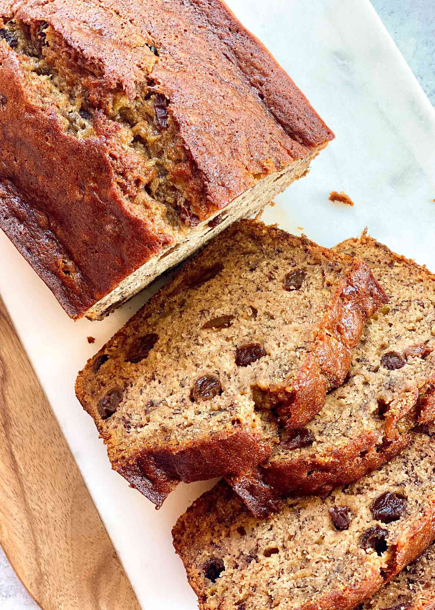 A loaf of rum raisin banana bread with four slices cut off and laying next to each other.