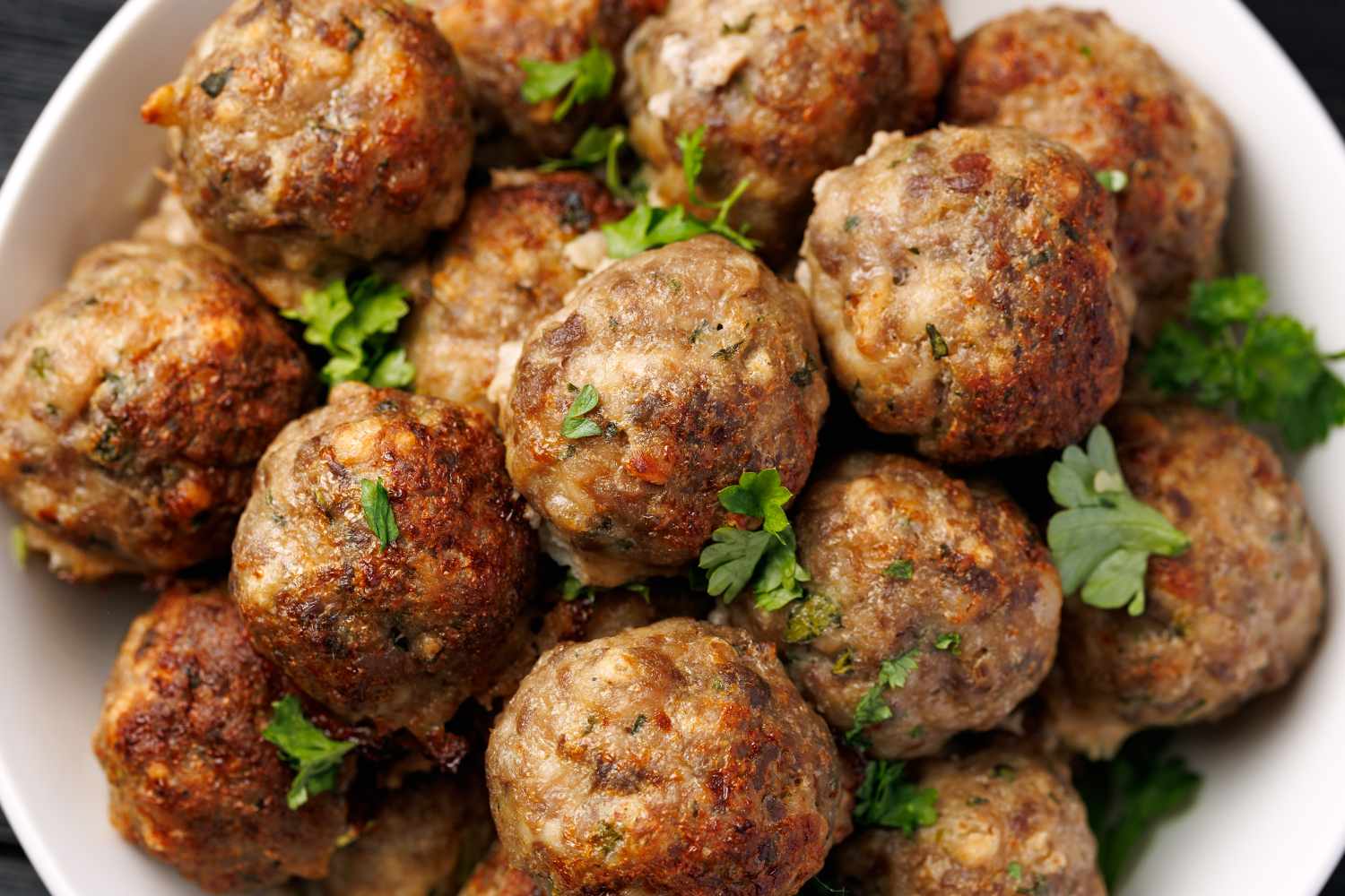 A dish of homemade meatballs garnished with parsley
