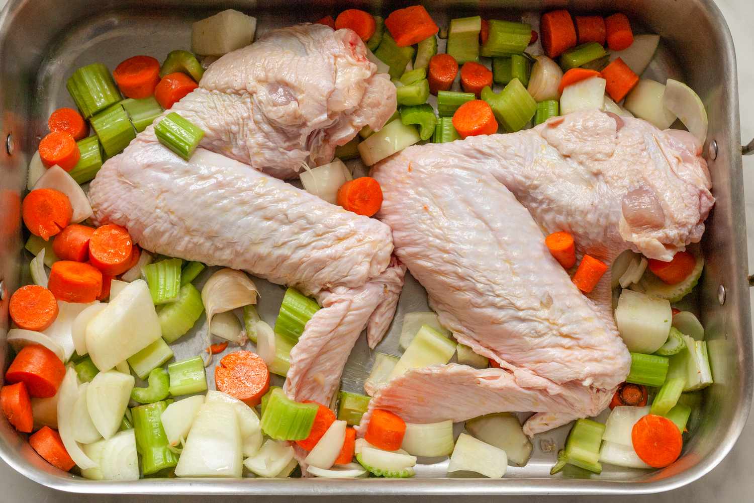 Raw turkey wings and vegetables in a roasting pan prepared for cooking