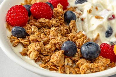 Closeup view of a bowl of granola topped with blueberries, strawberries and yogurt