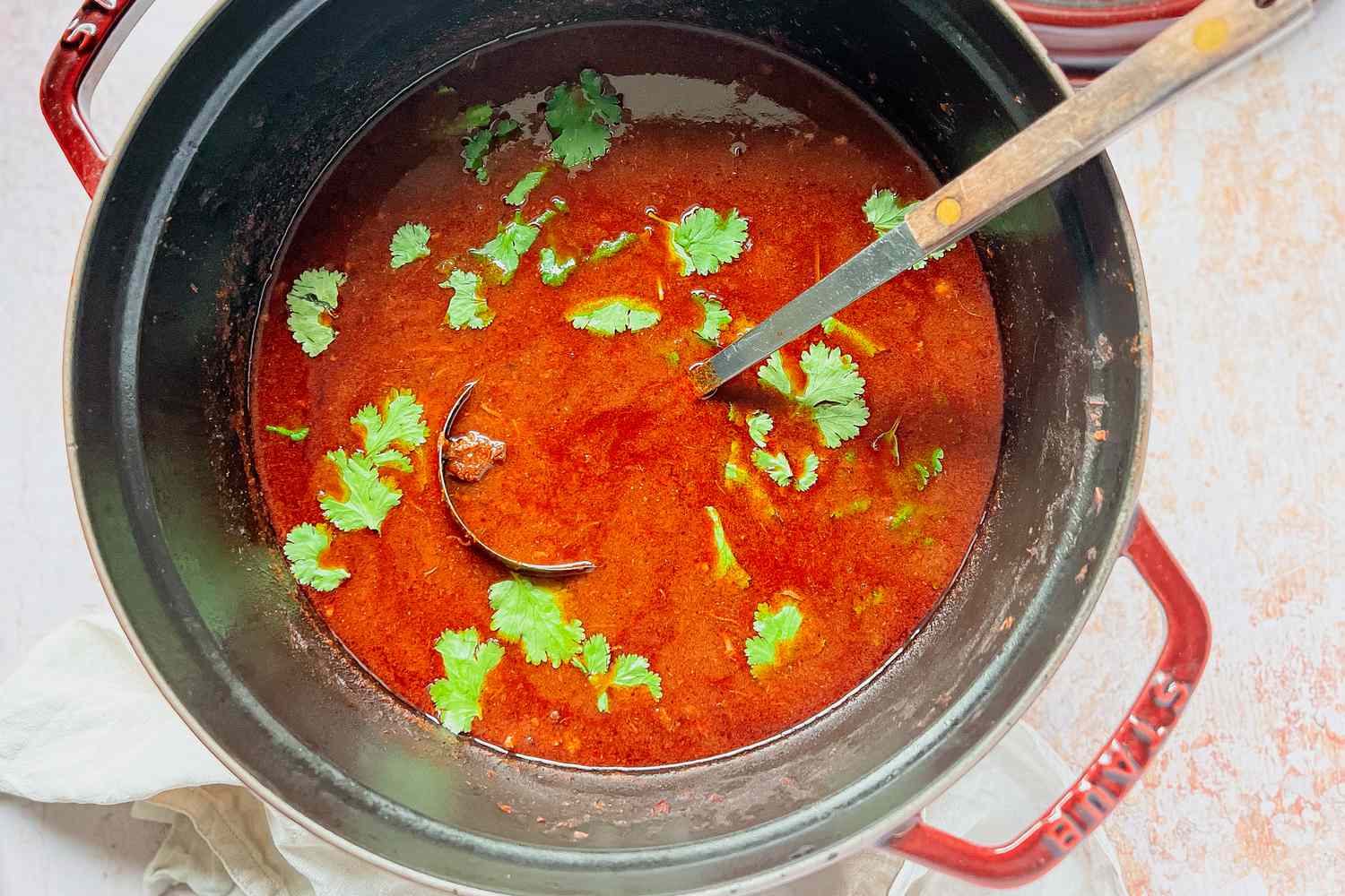 Birria being garnished with Cilantro in a Dutch oven