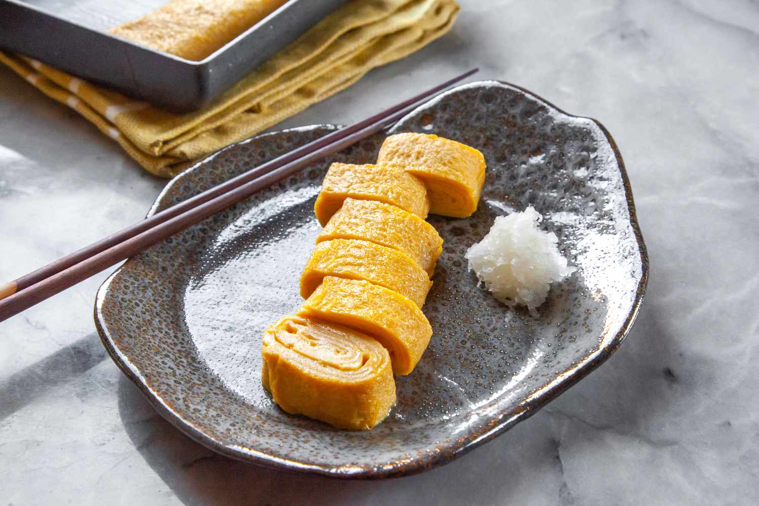 Tamagoyaki Cut into Pieces on Plate with Chopsticks