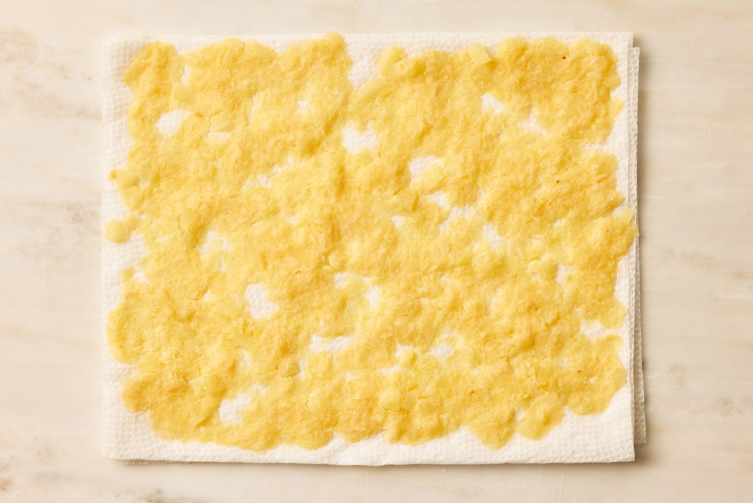 Overhead view of squeezed pineapple drying on a paper towel for Pig Pickin' Cake recipe