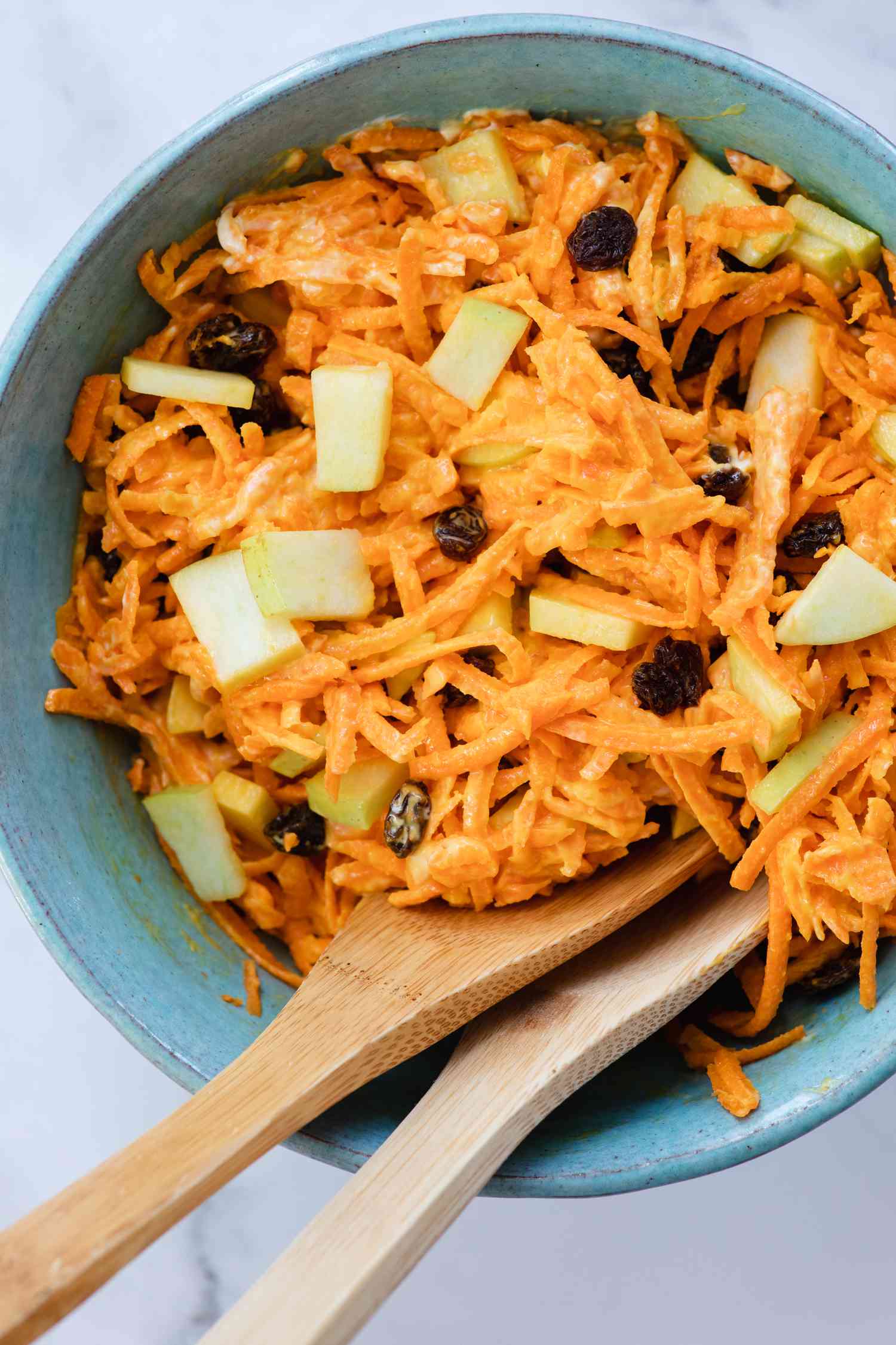 Classic Carrot Salad in a bowl with wooden serving spoons.