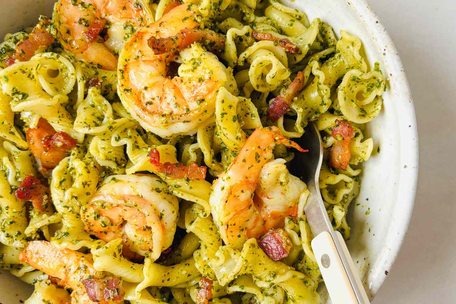 Shrimp pasta with pesto and a fork in a bowl