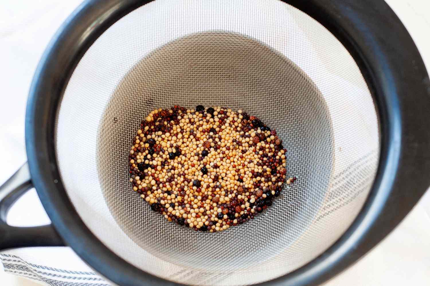 Making a honey mustard recipe and straining the mustard seeds.