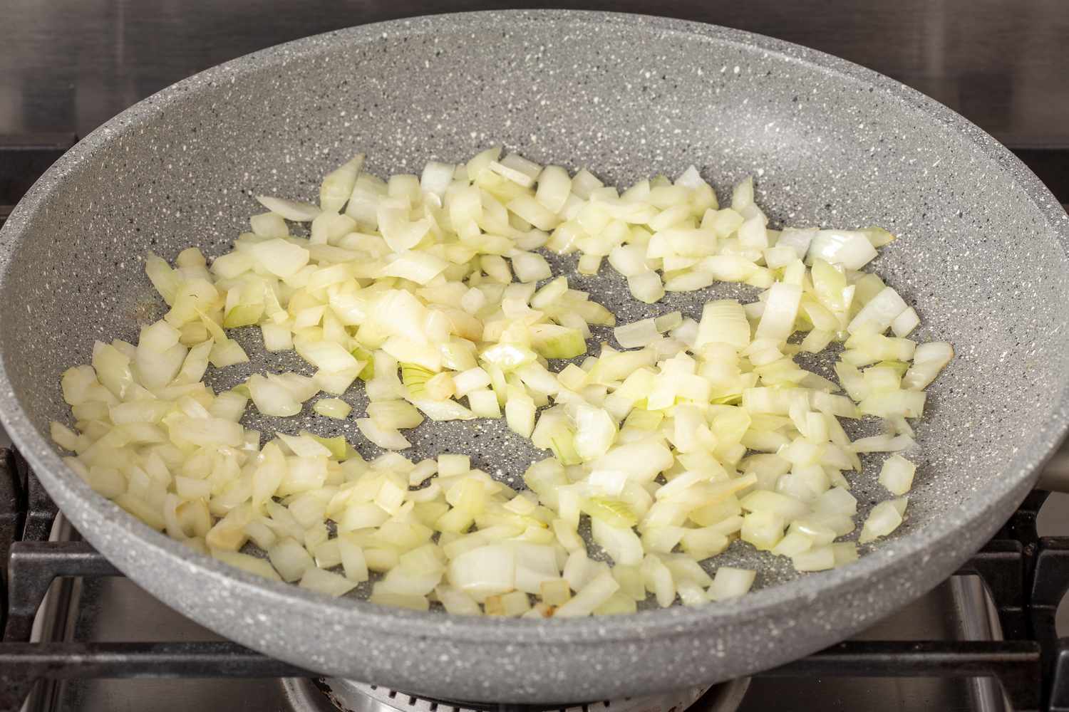 Sautéing onions in a skillet to make a refried beans recipe. 