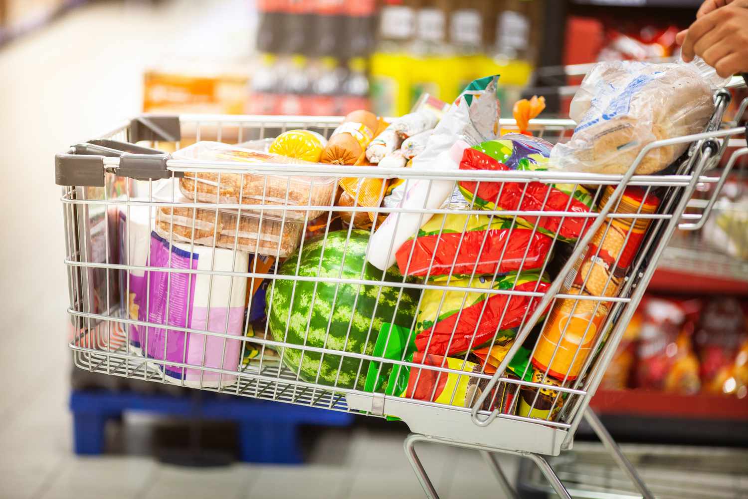 A shopping cart filled with grocery items in a supermarket aisle