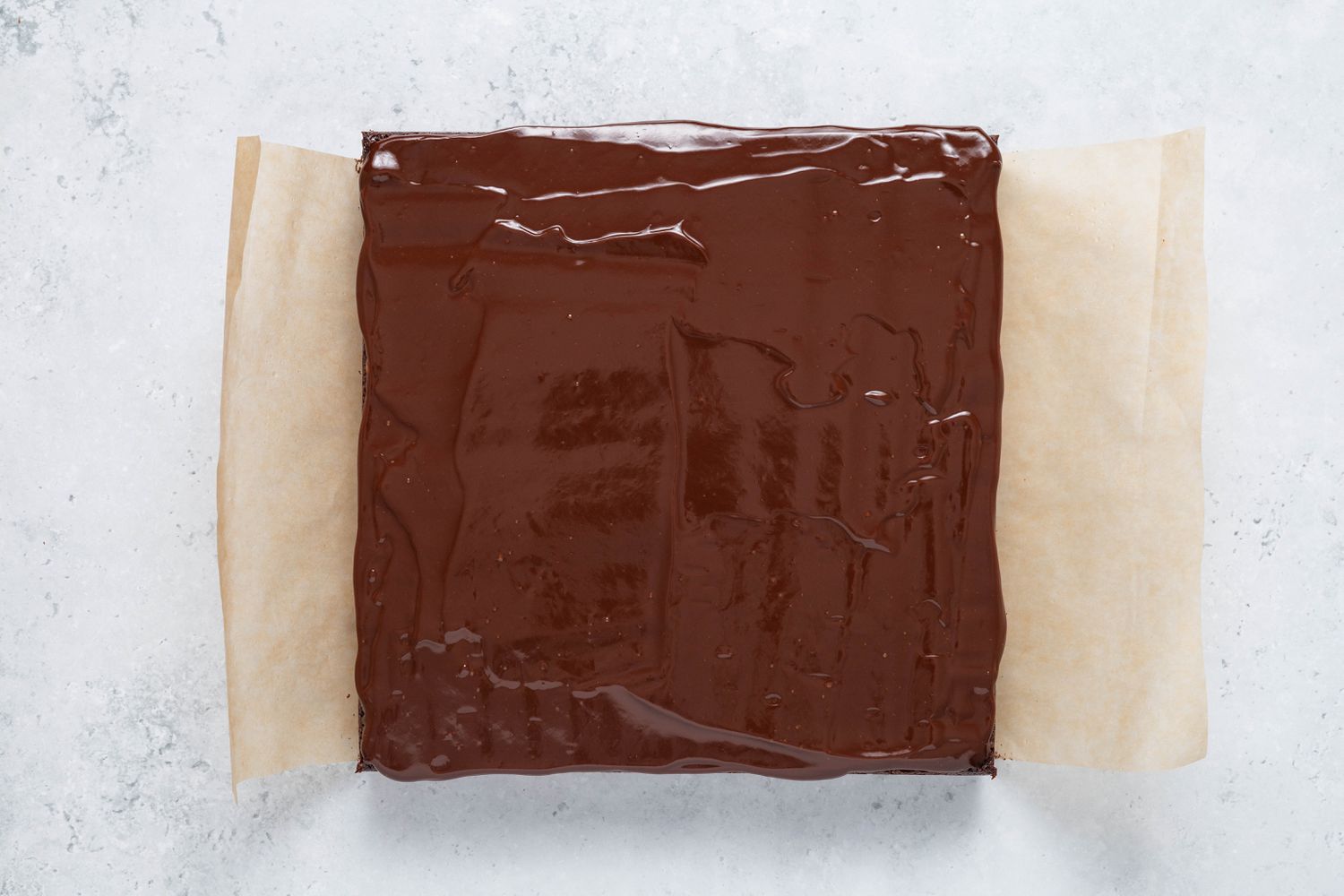 Ganache covered homemade Cosmic Brownie on a piece of parchment paper