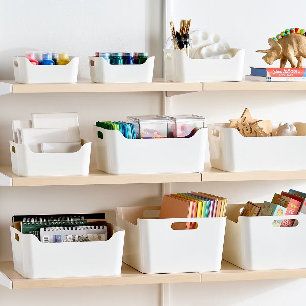 Plastic storage bins arranged on shelves holding various items such as stationery and craft materials