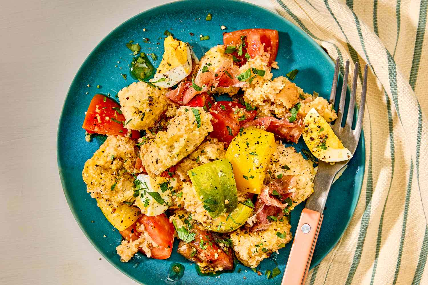 A plate of panzanella salad with bread, tomatoes, cucumber, and hard-boiled eggs