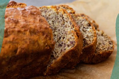 Photo of banana bread cut into slices on a piece of parchment with blue and yellow polka dots on the edges of the photo