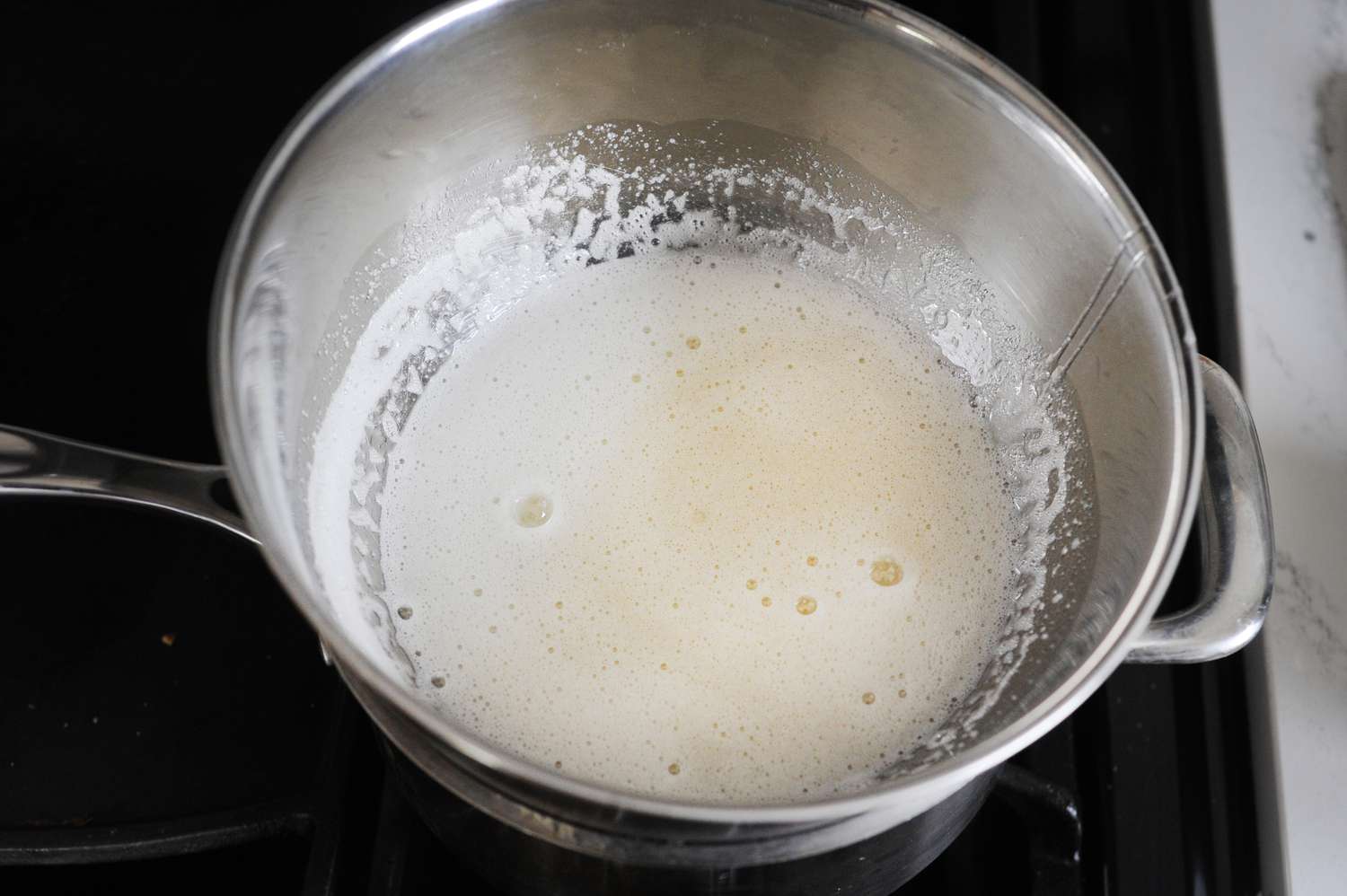 Frothy egg whites in a bowl to make No Fail Seven-Minute Frosting.