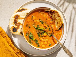 Easy Chickpea Curry in a bowl with a spoon, naan on the side