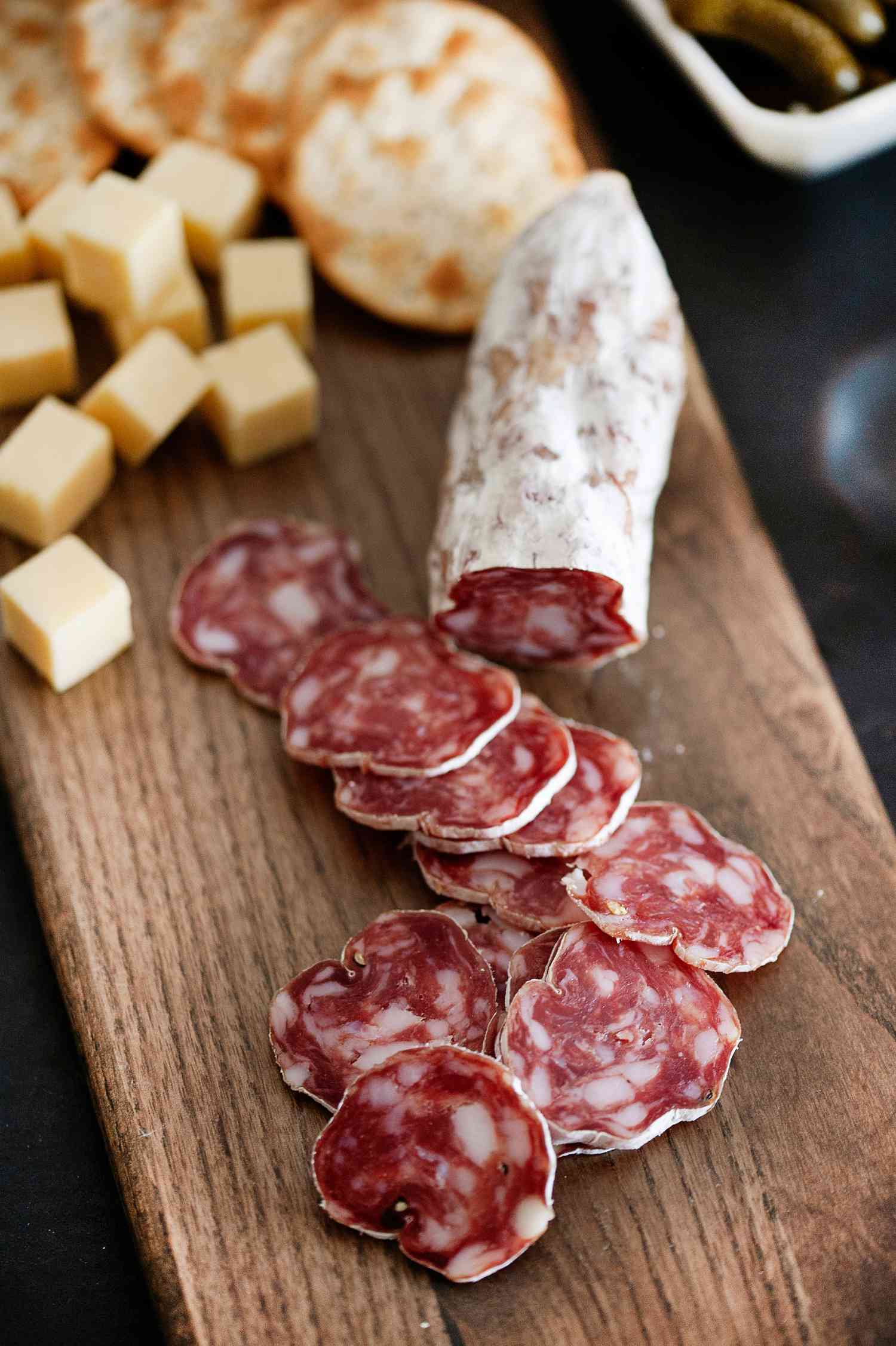 sliced soppressata link and crackers on cutting board