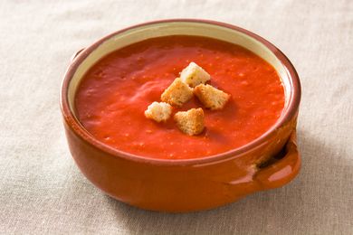 Tomato soup in brown bowl on tablecloth