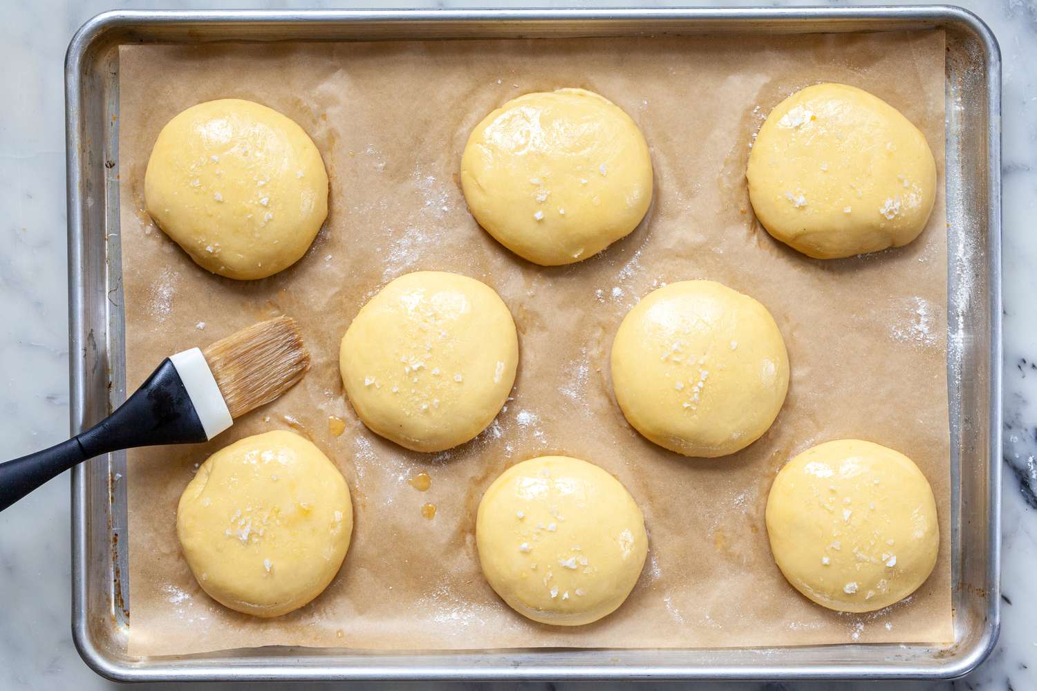 Coating dough balls for homemade hamburger buns in butter before baking.