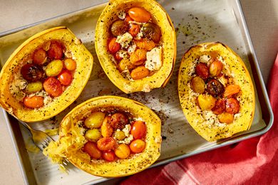 Overhead shot of four baked spaghetti squash stuffed with feta and cherry tomatoes, on a baking sheet