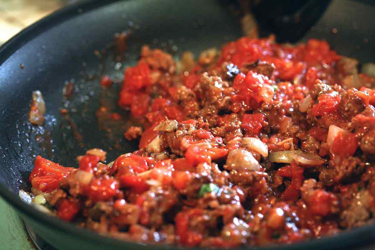 add tomatoes to the ground meat and onions for the penne pasta sauce