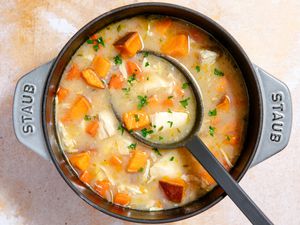 Overhead view of easy chicken stew in a gray dutch oven with a large serving spoon