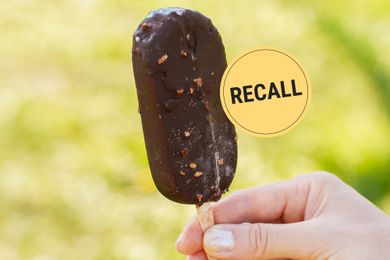 Hand holding a chocolatecovered ice cream bar next to a recall notice