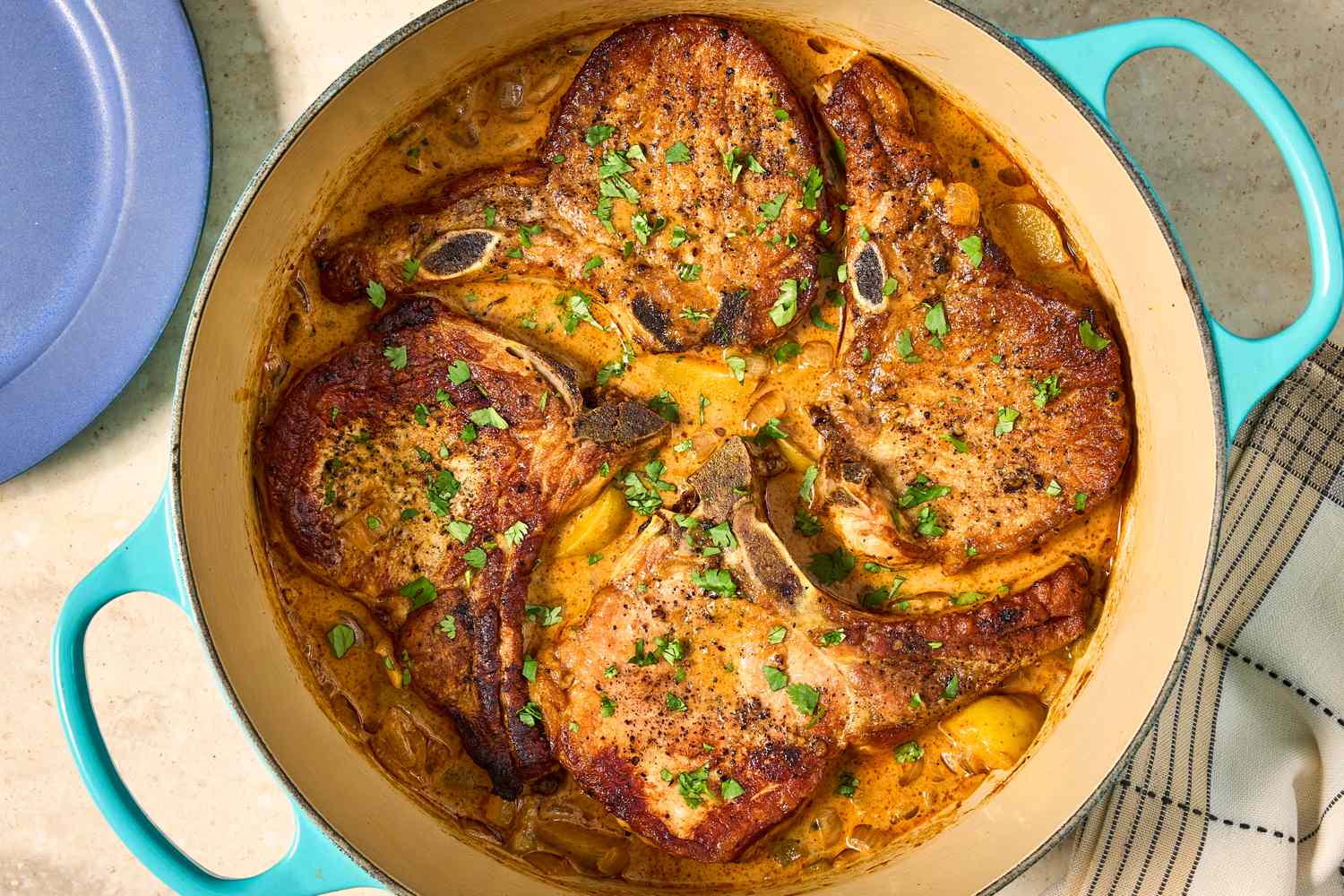 Cooked pork chops in a pot with sauce and garnishes