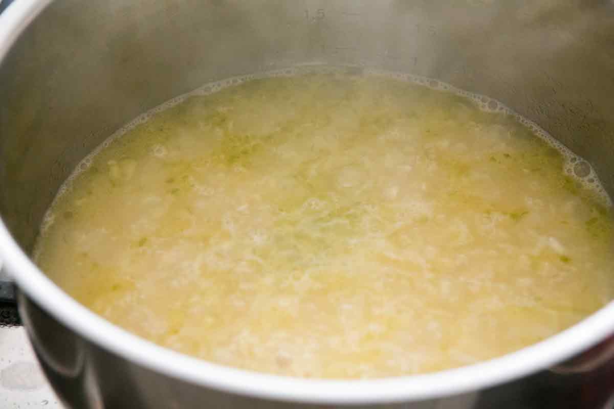 Water, salt, and lime zest added to rice and simmering in a pot