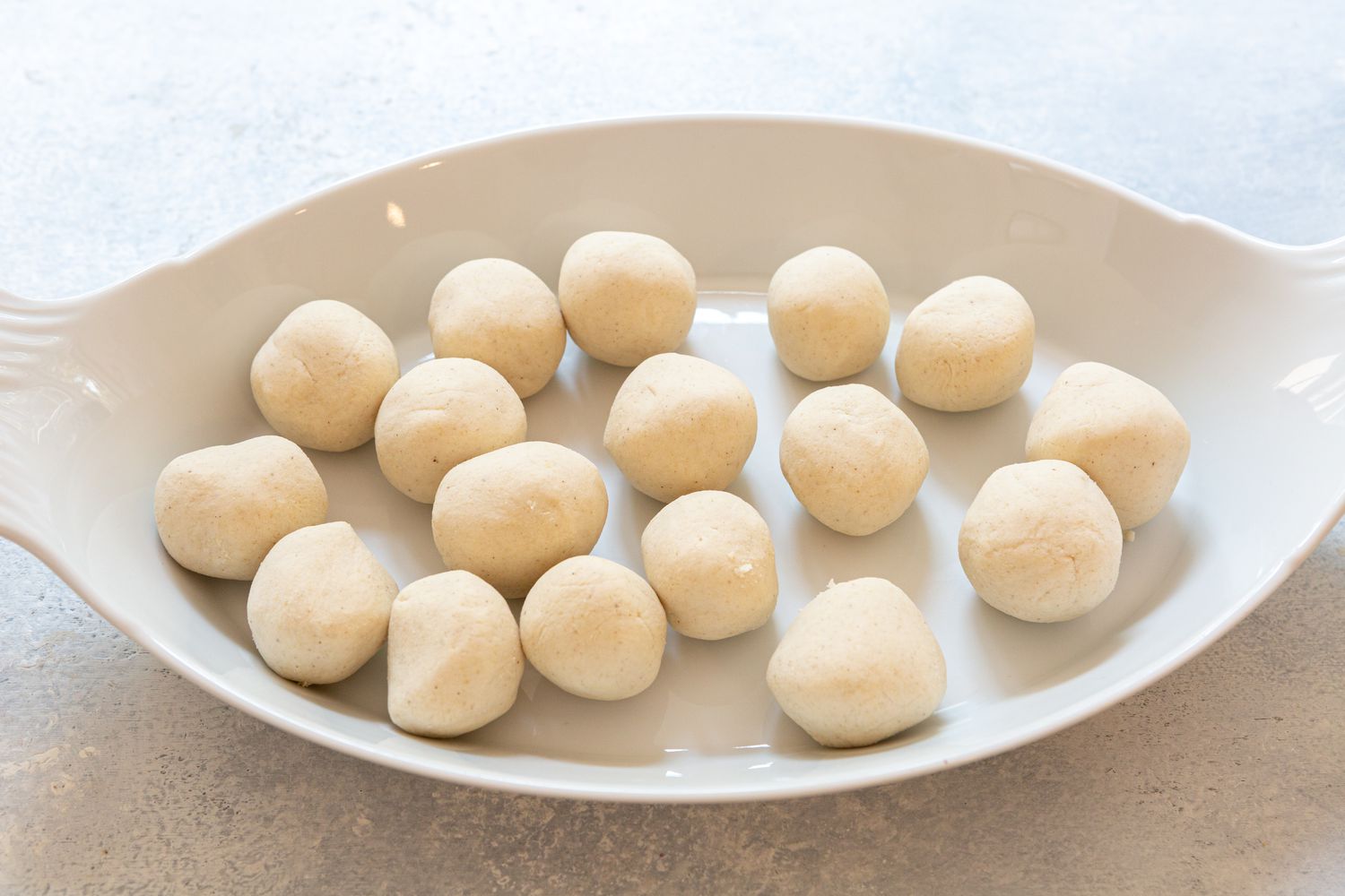 Balls of dough resting on a white platter 