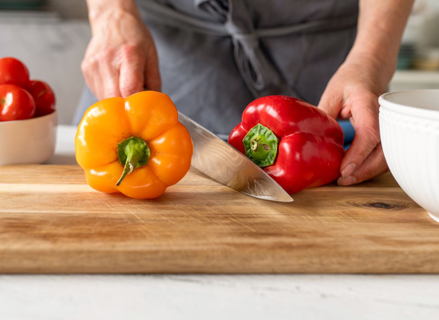 bell peppers on a cutting board with someone holding a knife