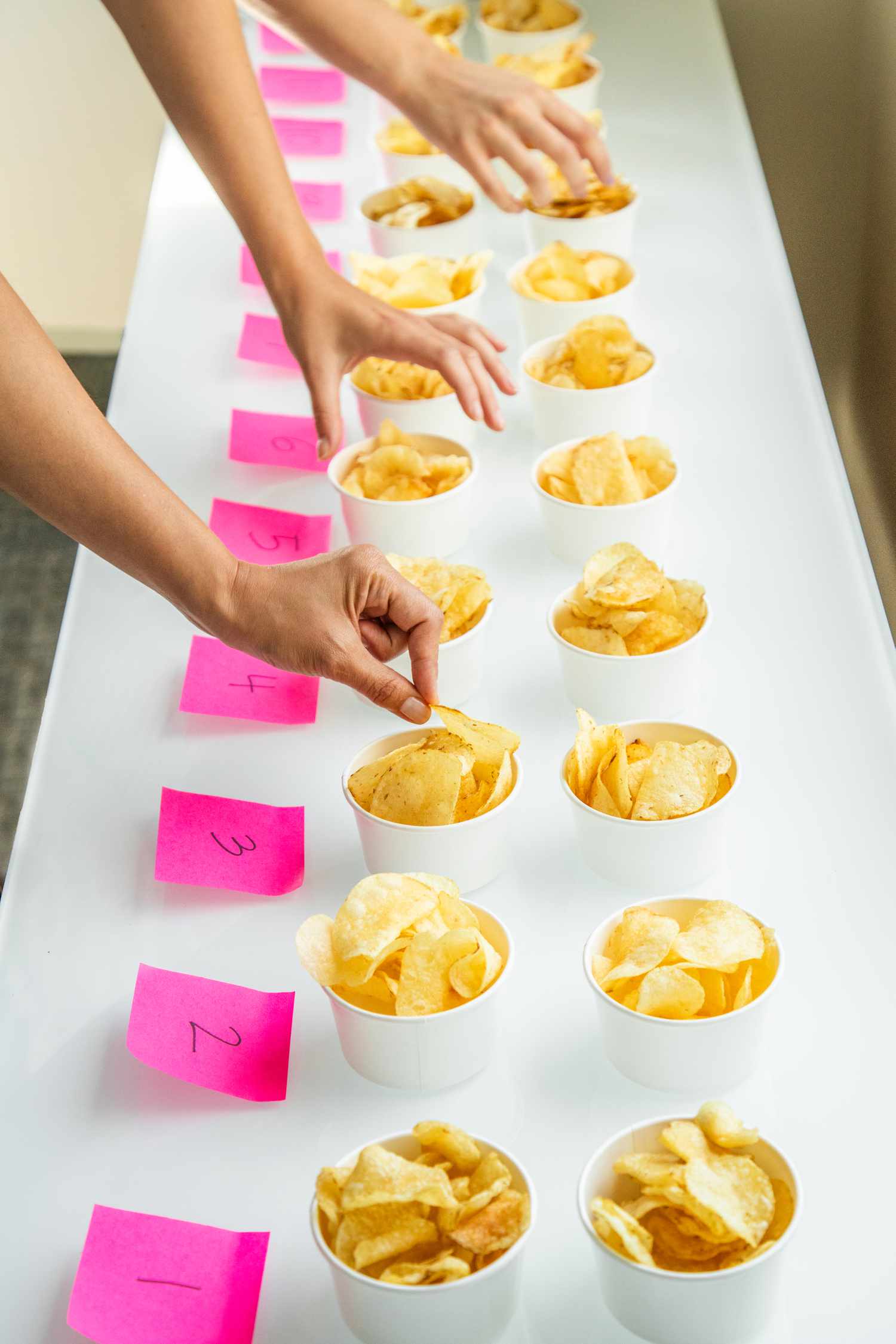 Arms reaching into potato chips in white cups