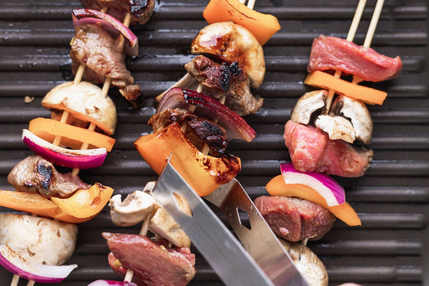 Putting beef kabobs on the grill.