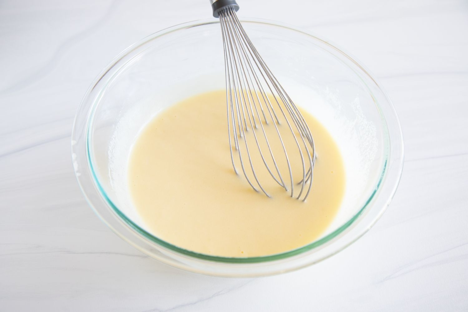 Yogurt Cake Recipe in a glass bowl with a whisk.