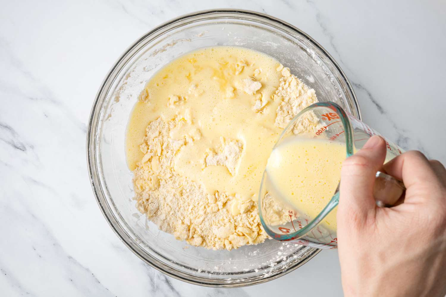 Measuring Cup of Buttermilk Poured into Bowl of Dry Ingredients for Scones with Lemon Recipe