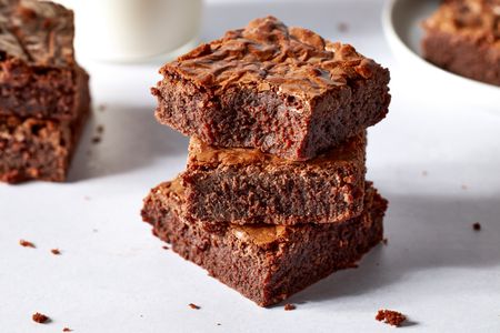 Side view of three brownies stacked on top of each other with a bite bitten from the brownie at the top